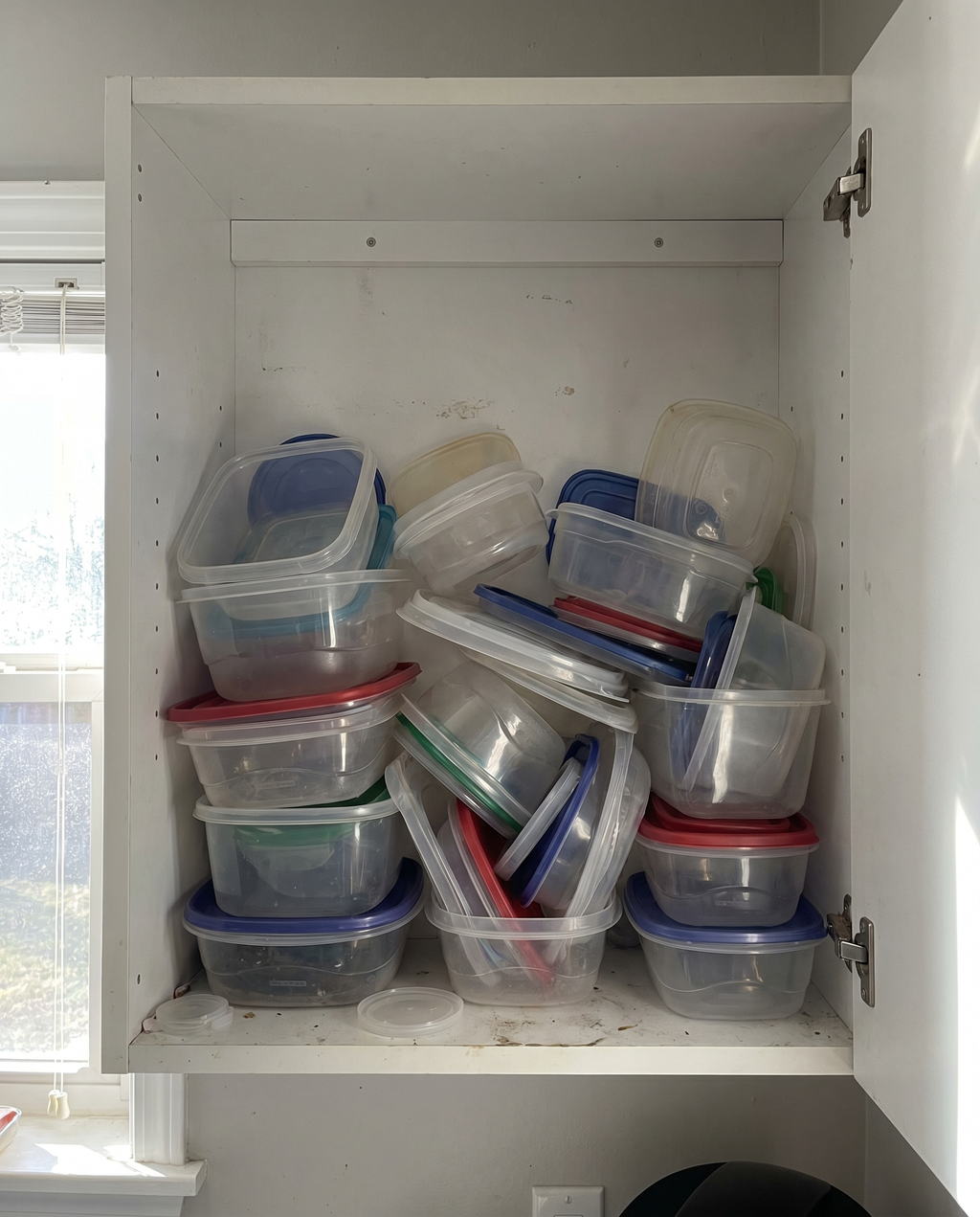Before: cluttered cabinet of mismatched food container lids